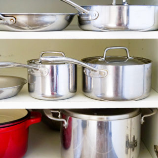 Five stainless steel Tramontina pots and pans in cupboard