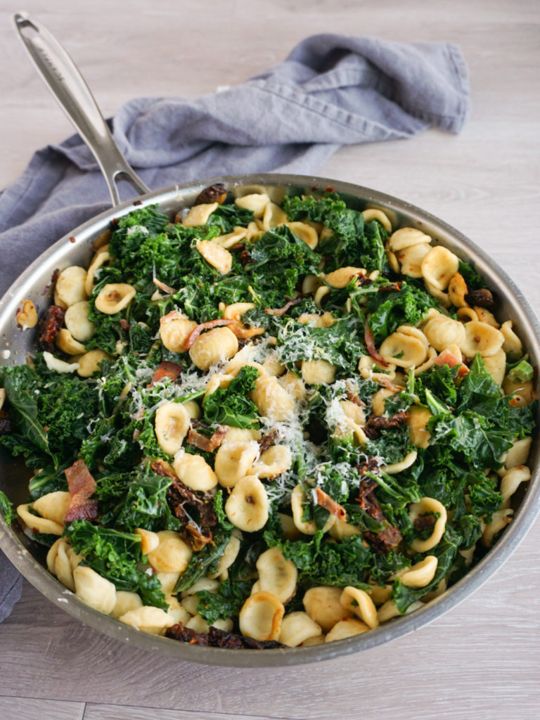 Orecchiette with Kale, Bacon, and Sun-Dried Tomatoes in pan with grey tea towel