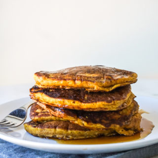 Easy homemade pumpkin walnut pancakes on white plate with maple syrup