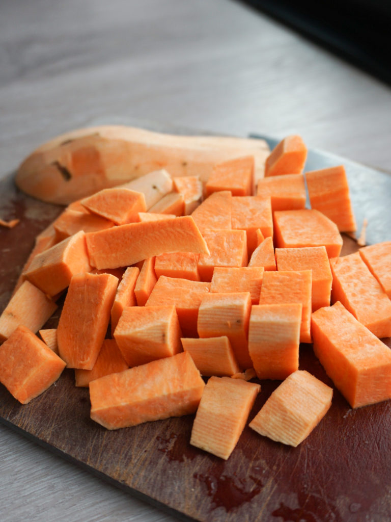 Chopped sweet potato on cutting board for spiced chickpea stew with coconut