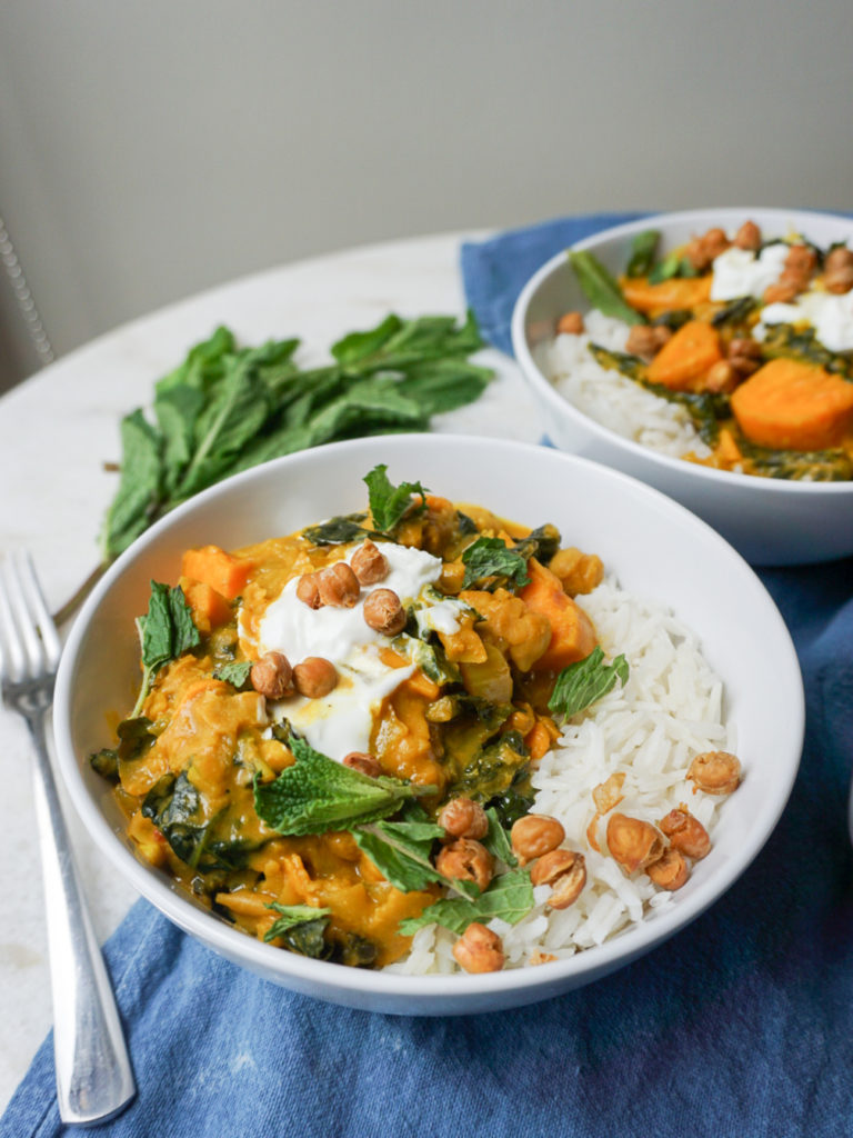 Spiced Chickpea stew with Sweet Potato, Coconut, Cumin, and turmeric in two white bowls on white table