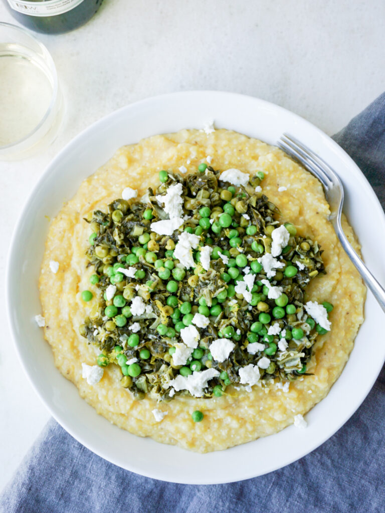 Easy polenta recipe with spinach, peas, and goat cheese in white dish
