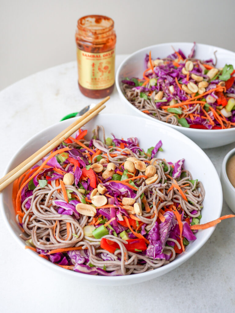Asian noodle salad with peanut sauce and cabbage in white bowls