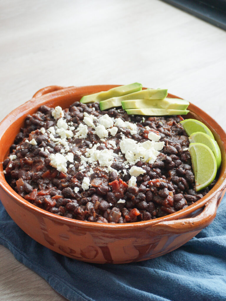 overnight smoky black beans in dish with feta, lime, and avocado
