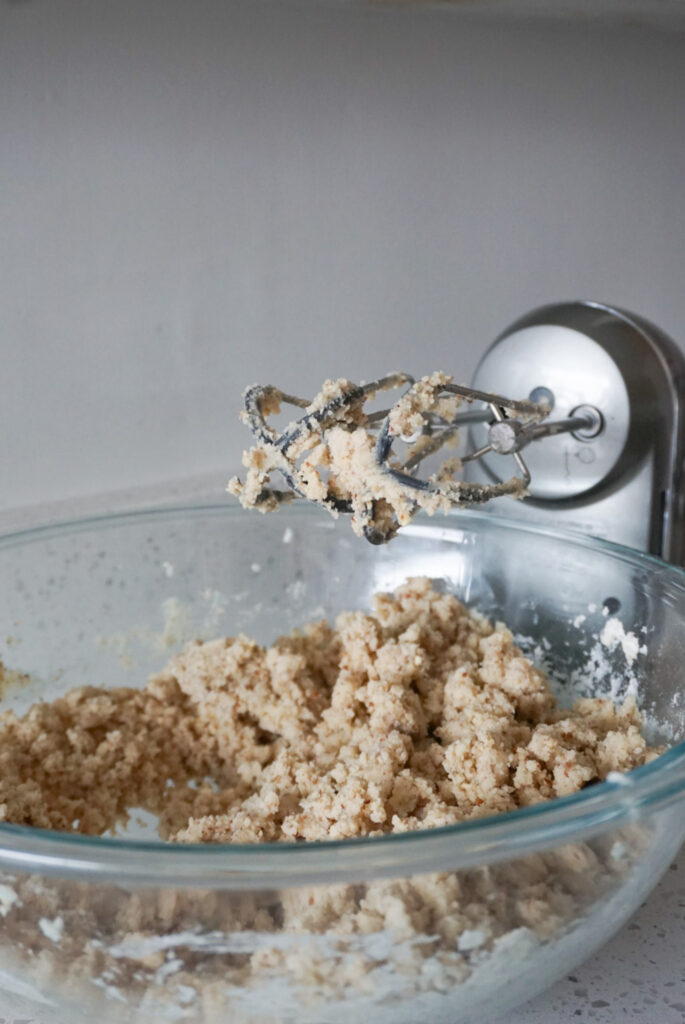 Pecan Linzer cookie dough in mixing bowl with hand mixer