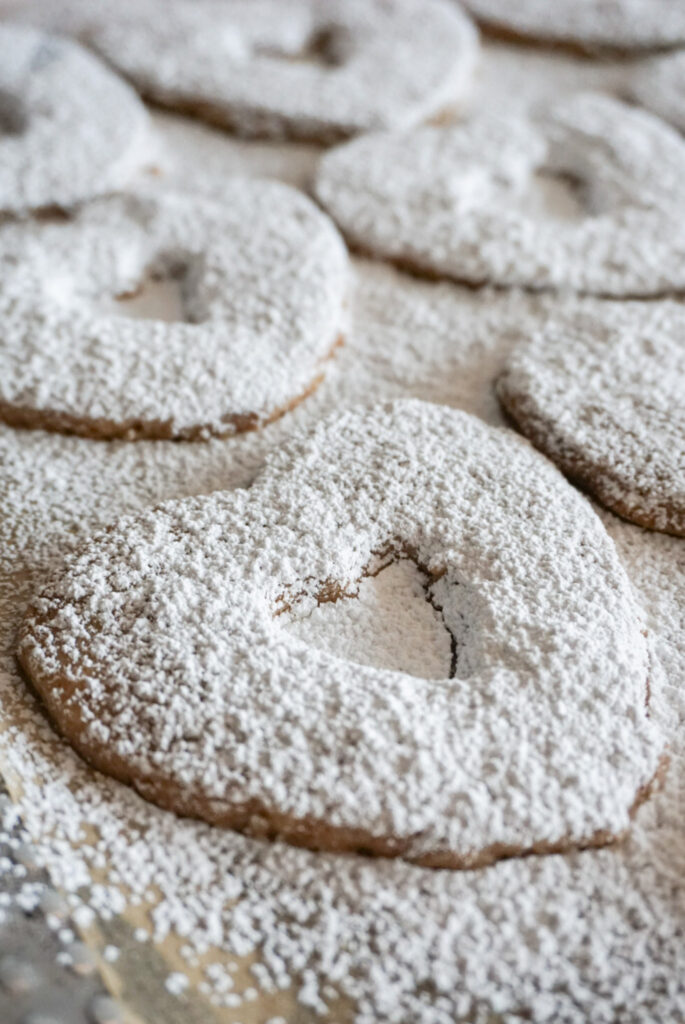 Pecan and raspberry Linzer cookies covered in powdered sugar